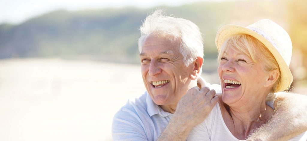 Older couple smiling at the beach.
